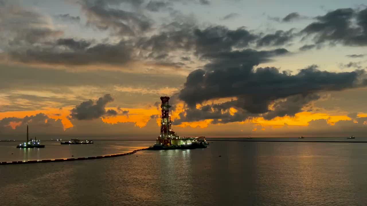 Offshore production platform at dusk, with supply vessels on the horizon